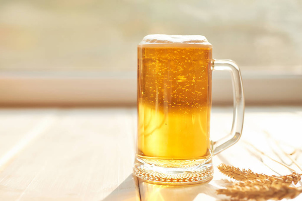 glass of beer on a white wooden background, view from the window at sunset, oktoberfest - Photo, Image