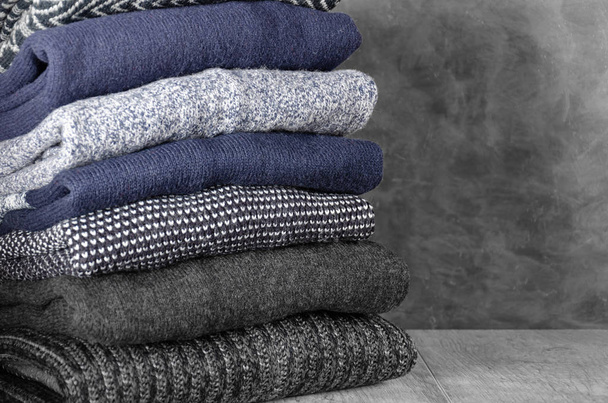 Pile de pulls chauds pliés pour hommes en tricot sur fond gris. Gros plan. Espace de copie
 - Photo, image