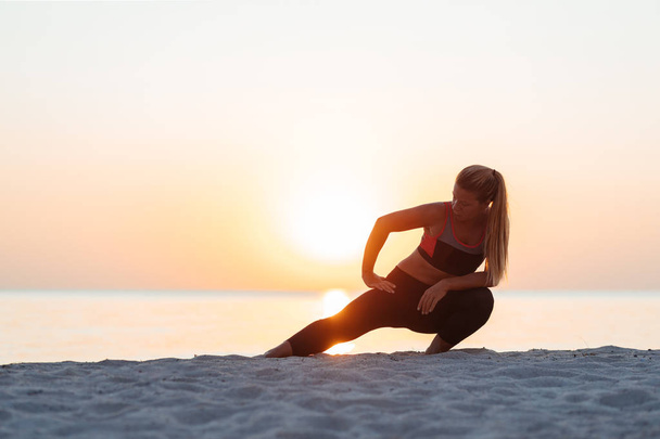 Young woman at the beach in sunset stretching after workout - Photo, Image