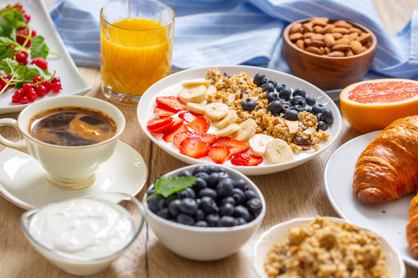 Egészséges reggeli szolgált tányér joghurt müzli fekete áfonya eper és banán. - Fotó, kép