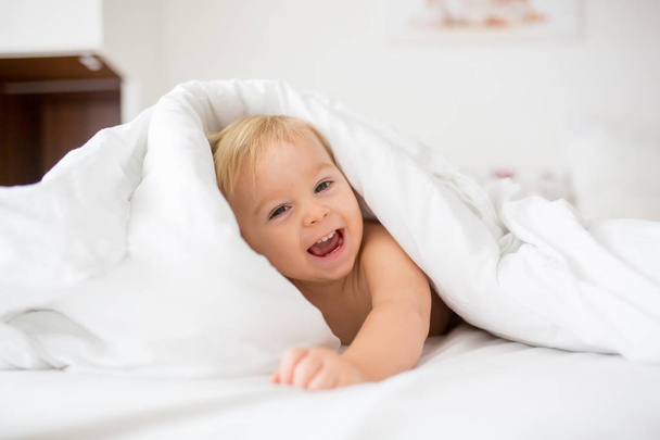 Cute little baby boy, relaxing in bed after bath, smiling happil - Foto, imagen