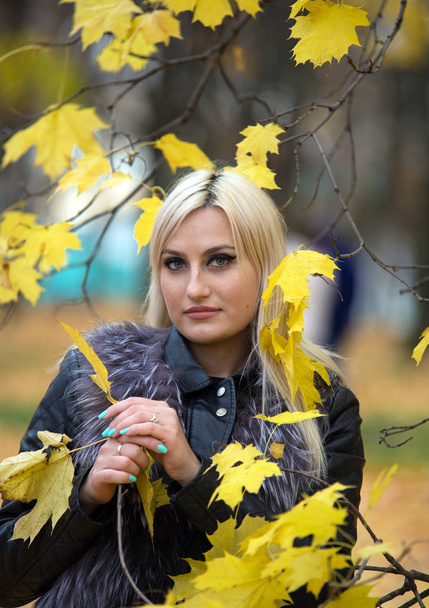 2017.10.21, Moscow, Russia. A young attractive woman wearing fur black jacket walking around autumn park. - Fotografie, Obrázek