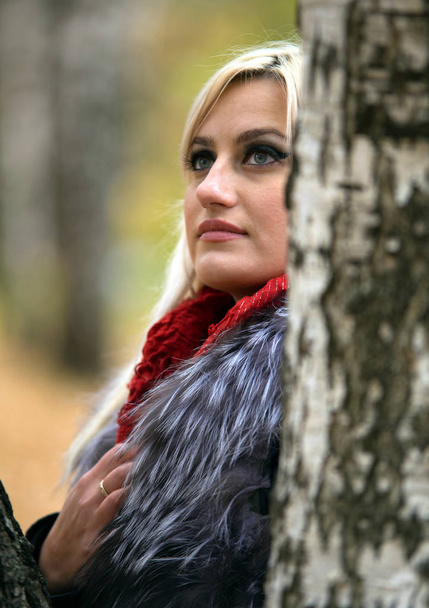 2017.10.21, Moscow, Russia. A young attractive woman wearing fur black jacket standing by the tree. Walking around autumn park. - Fotografie, Obrázek