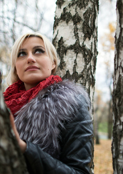 2017.10.21, Moscow, Russia. A young attractive woman wearing fur black jacket standing by the tree. Walking around autumn park. - Fotoğraf, Görsel