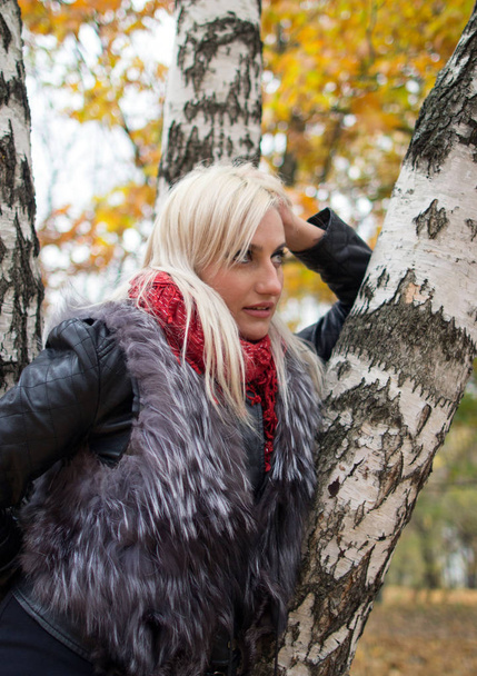 2017.10.21, Moscow, Russia. A young attractive woman wearing fur black jacket standing by the tree. Walking around autumn park. - Фото, зображення