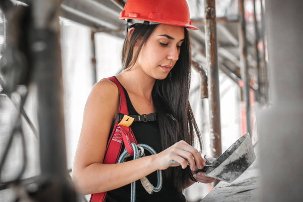 Female construction mason on the scaffolding, plastering and renovating building - Foto, Bild