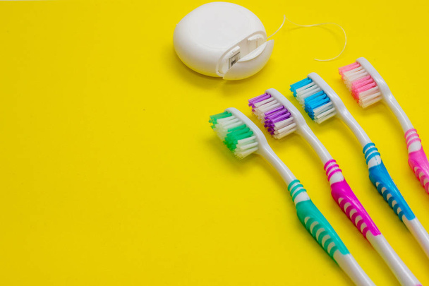 Quatro escovas de dentes multicoloridas e fio dental sobre fundo branco
 - Foto, Imagem