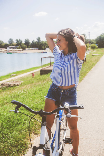  自然の中で自転車に乗る若い女性 - 写真・画像
