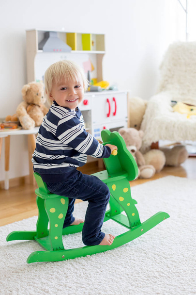 Little cute toddler boy, playing with rocking frog swing at home - Fotó, kép