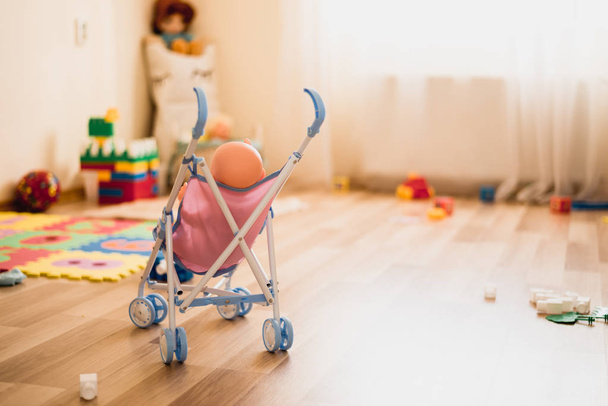 Stroller with doll in playroom. Copy space for text. Creative play for kids. Daycare - Fotó, kép