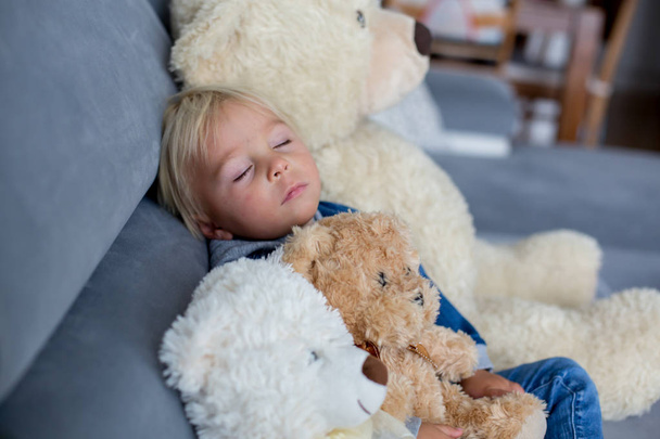 Blond toddler boy, sleeping with many teddy bears in the afterno - Фото, зображення