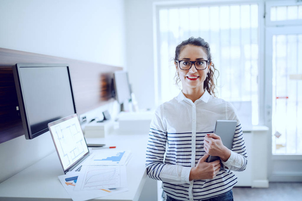 fröhliche attraktive kaukasische Geschäftsfrau mit Brille und Pferdeschwanz, lässig gekleidet, mit Tablet in der Hand im Büro. - Foto, Bild
