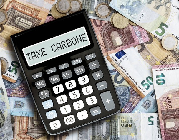 text TAXE CARBONE, French for carbon tax, on display of pocket calculator against euro bills on table - Photo, Image
