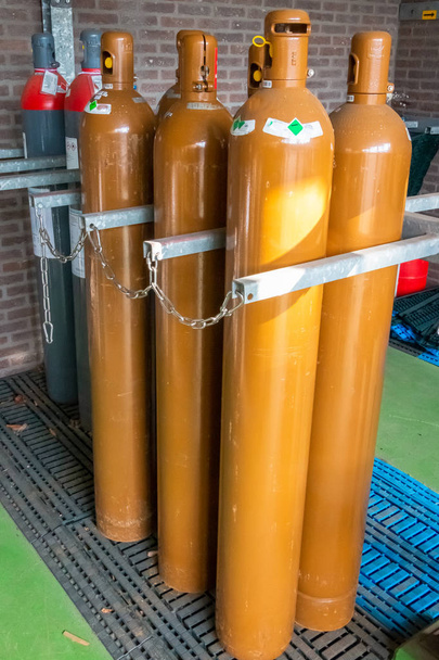 Almacenamiento industrial de botellas de gas, enganchado y encadenado por razones de seguridad, fotografía tomada en los Países Bajos
 - Foto, Imagen