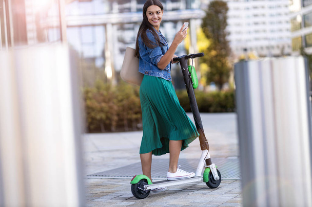 Carefree young woman riding an electric scooter - Photo, Image