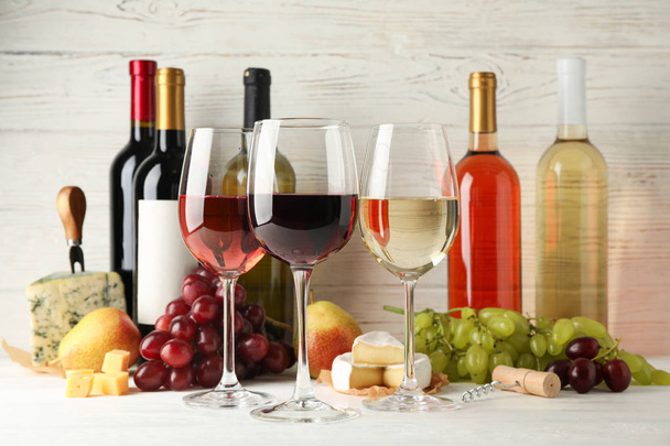 Фрукты, сыр, бутылки и бокалы с различными винами на белом
 - Фото, изображение