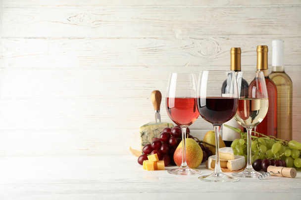 Fruits, cheese, bottles and glasses with different wine on white - Foto, imagen
