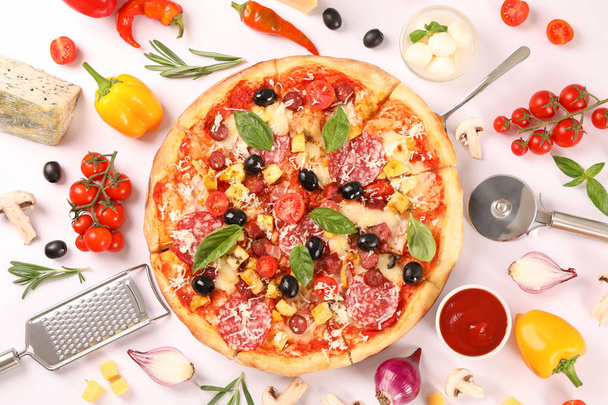 Platte lag. Smakelijke pizza, ingrediënten en keuken benodigdheden op wit - Foto, afbeelding