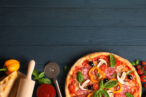Deliciosa pizza e ingredientes sobre fondo de madera, espacio para copiar
 - Foto, Imagen