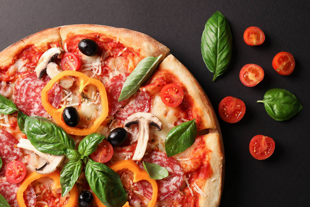 Delicious pizza and tomatoes on dark background, close up - Foto, Imagen