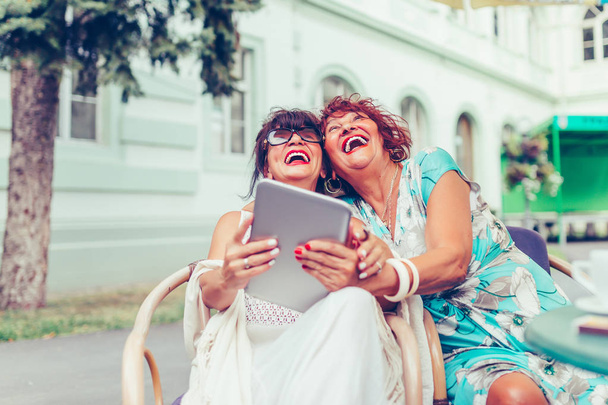 İki üst düzey kadın gülüyor ve sosyal medya ve komik vi izliyor - Fotoğraf, Görsel