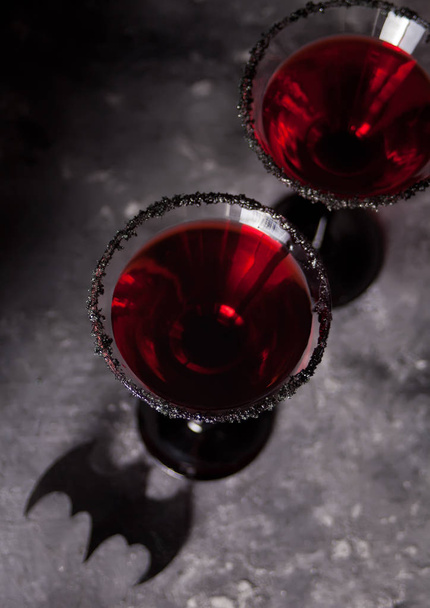 Two glasses with red cocktail for Halloween party on the dark background - Fotó, kép