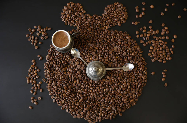 ローストコーヒー豆を背景にカップにフラットなアロマエスプレッソを置きます。コーヒー豆目覚まし時計。コーヒーブレイクやコーヒータイムのコンセプト。コーヒー豆の背景コンセプト。トップビュー. - 写真・画像