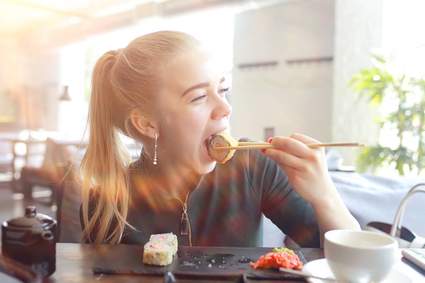 girl eats sushi and rolls in a restaurant / oriental cuisine, Japanese food, young model in a restaurant - Fotoğraf, Görsel