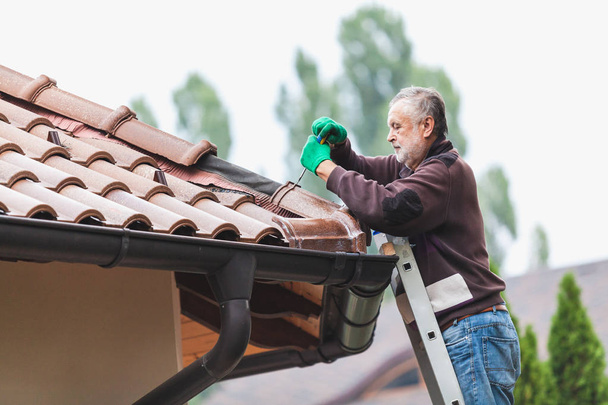 Man repairs a tiled roof of house close up - Foto, Imagem