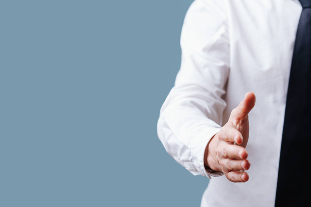 Businessman in white shirt extending hand, ready for handshake over blue - Foto, Imagem