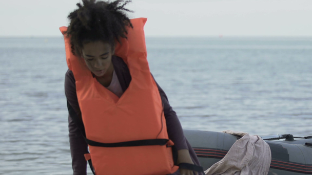 Ragazza afro-americana in barca che si toglie il giubbotto di salvataggio, sopravvissuta dopo il naufragio
 - Filmati, video