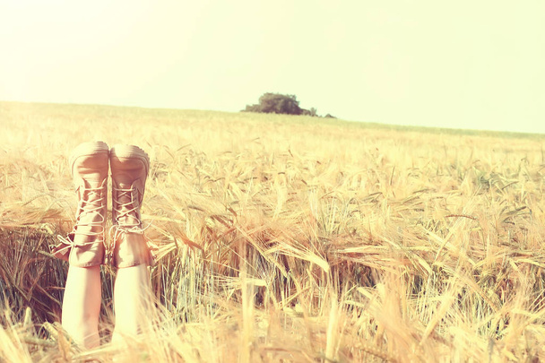girl lies in the field with her legs up in boots / legs stick out in the field, the concept of leisure happiness - Photo, Image
