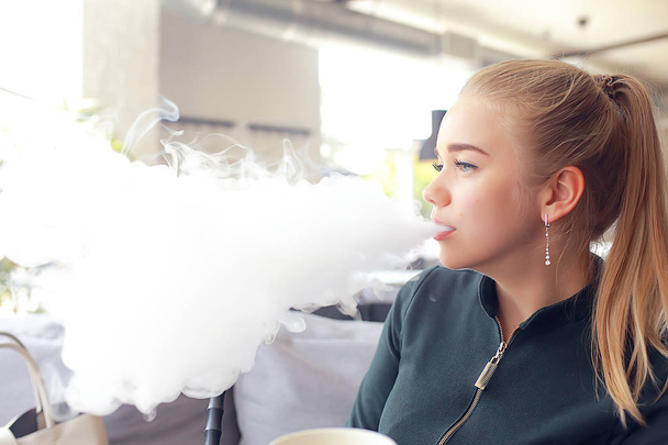 girl smokes a hookah at the bar / smoking, health, modern cigarettes vape - Фото, зображення