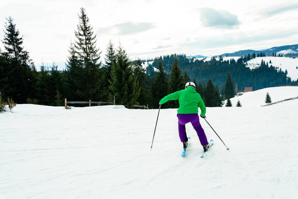 Jeune homme en veste verte et pantalon violet ski
. - Photo, image
