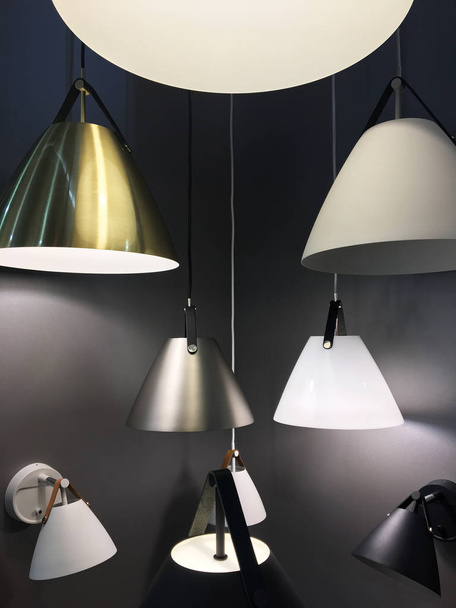 Display of many hanging lamps with colorful lamp shade sizes and colors in dark room. A group of hanging lights with shallow depth of field. Installation. Many lampshades - Zdjęcie, obraz