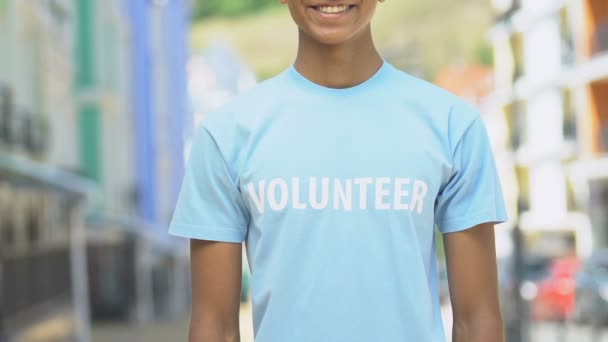 Volunteer in shirt folding arms smiling outdoors, charity advertising closeup - Séquence, vidéo