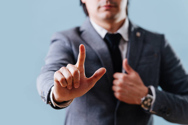 Geschäftsmann im Anzug macht Einspruch-Geste, hebt Zeigefinger über Blau - Foto, Bild