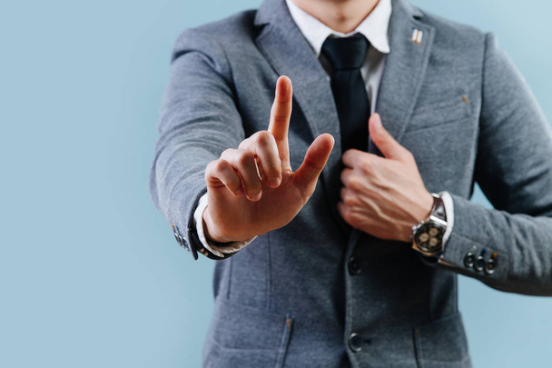 Businessman in suit making objection gesture , holding index finger up over blue - Photo, Image