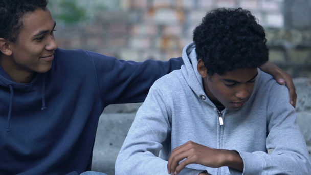 czarny mężczyzna nastolatek próbuje przytulić obrażony przyjaciel próba pojednania - Materiał filmowy, wideo