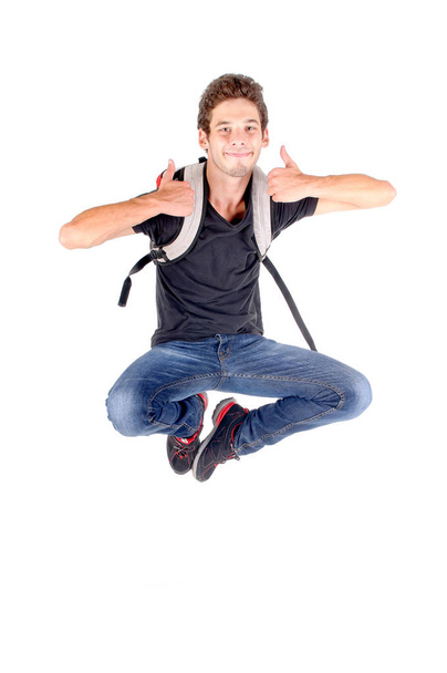 teenage boy jumping isolated in white and showing thumbs up - Fotó, kép