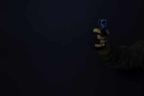 asian man holds a gun. Gun in his hand. Killed shooting his target isolated on black background. - Photo, Image