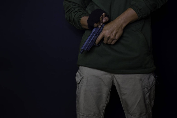 азіатський чоловік тримає пістолет. Пістолет у руці. Вбитий стрілянина його мішень ізольовано на чорному тлі
. - Фото, зображення