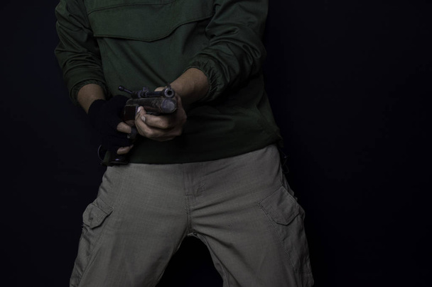 ázsiai ember tartja a fegyvert. Gun a kezében. Megölték lövés a cél elszigetelt fekete háttér. - Fotó, kép