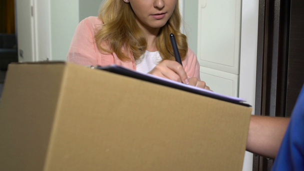 Houkutteleva nainen vastaanottaa paketin pahvilaatikossa ja allekirjoittaa asiakirjojen toimitus
 - Materiaali, video