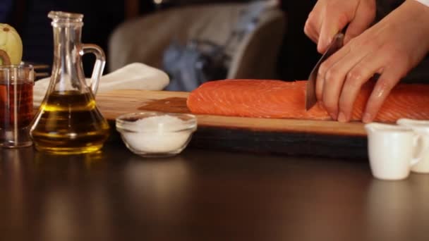 Szef kuchni tnie duży kawałek surowego filet z łososia. Żywność wysokobiałkowa - Materiał filmowy, wideo