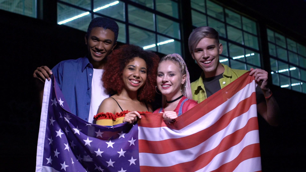 Dos parejas de adolescentes multirraciales sosteniendo bandera de EE.UU., patriotas del país, slow-mo
 - Metraje, vídeo