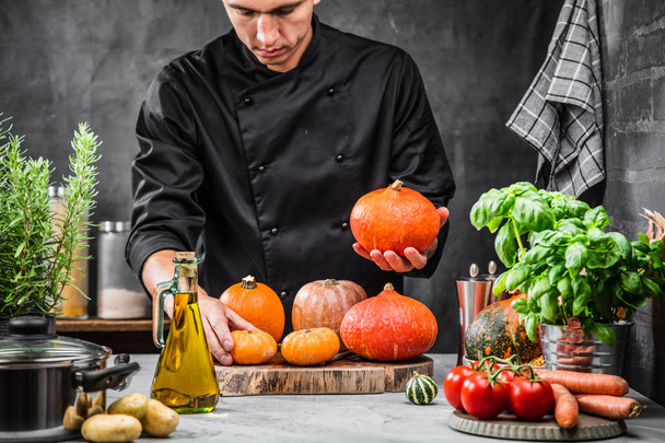 cropped shot of male chef holding ripe pumpkin in kitchen    - Foto, afbeelding