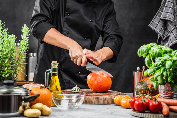 cropped shot of male chef cutting pumpkin in kitchen  - Zdjęcie, obraz