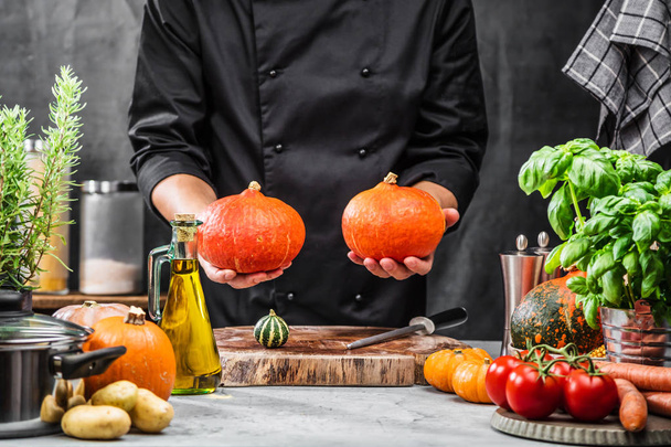cropped shot of male chef holding ripe pumpkins in kitchen  - Φωτογραφία, εικόνα