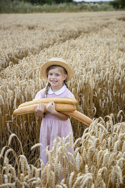 Mała dziewczynka trzyma okrągły chleb. Ręce trzymujące duży chleb. Piekarnia - Zdjęcie, obraz